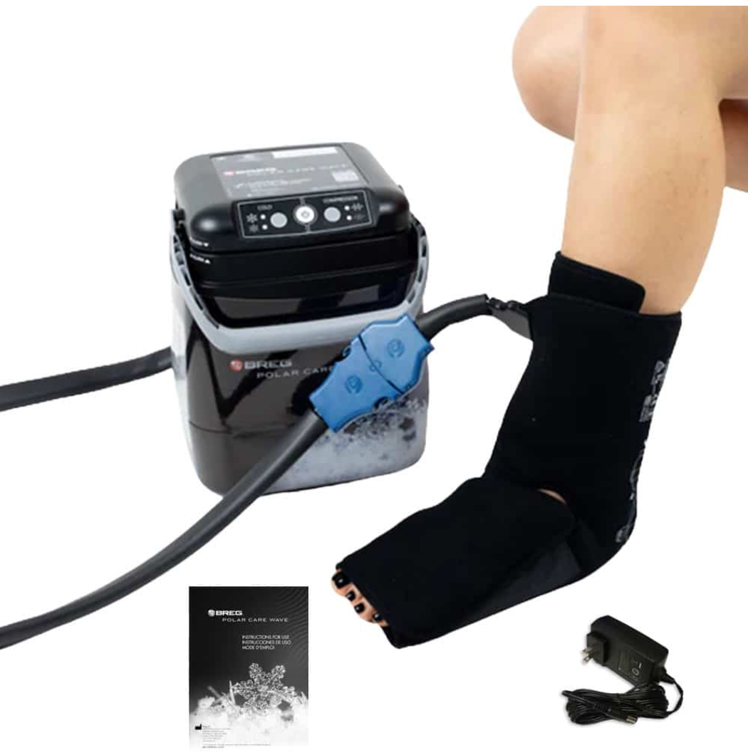 Breg Polar Care Wave cold therapy system in use on ankle with ankle wrap pad, pump unit, blue quick-connect tubing, power adapter, and instruction manual
