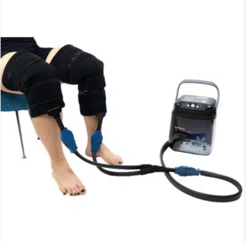 Breg Polar Care Wave cold therapy system in use on both knees simultaneously with dual knee wrap pads and blue quick-connect tubing connected to pump unit

