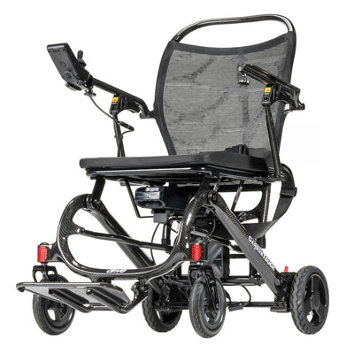 Drive Carbon Touch folding electric wheelchair 3/4 rear view showing carbon fiber frame, mesh backrest, joystick controller, battery pack, pneumatic rear wheels, front casters, footrests, and red reflectors — available at Must in Metro Vancouver