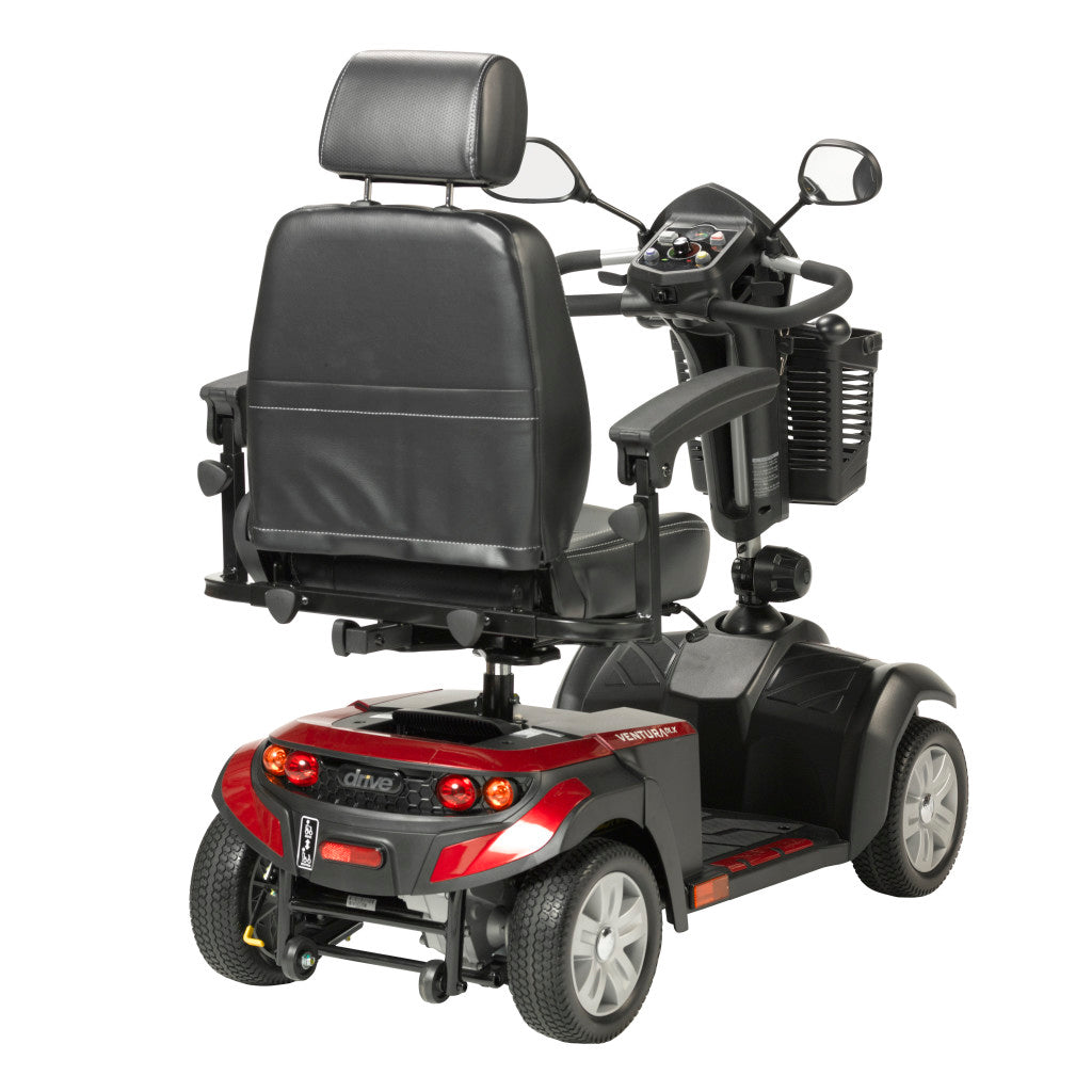 Rear 3-quarter view of Drive Ventura 4-wheel mobility scooter in red and black showing captain seat back, headrest, tail lights, tiller control panel, and all-terrain tires
