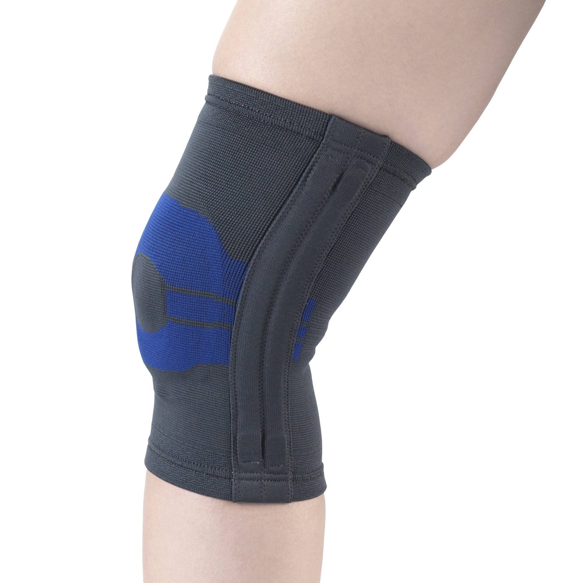 Grey and blue knitted knee compression sleeve with viscoelastic insert pad, lateral spiral stays, and ribbed cuffs worn on leg — side view showing anatomically contoured patella support, structured side stabilizers, and full knee coverage