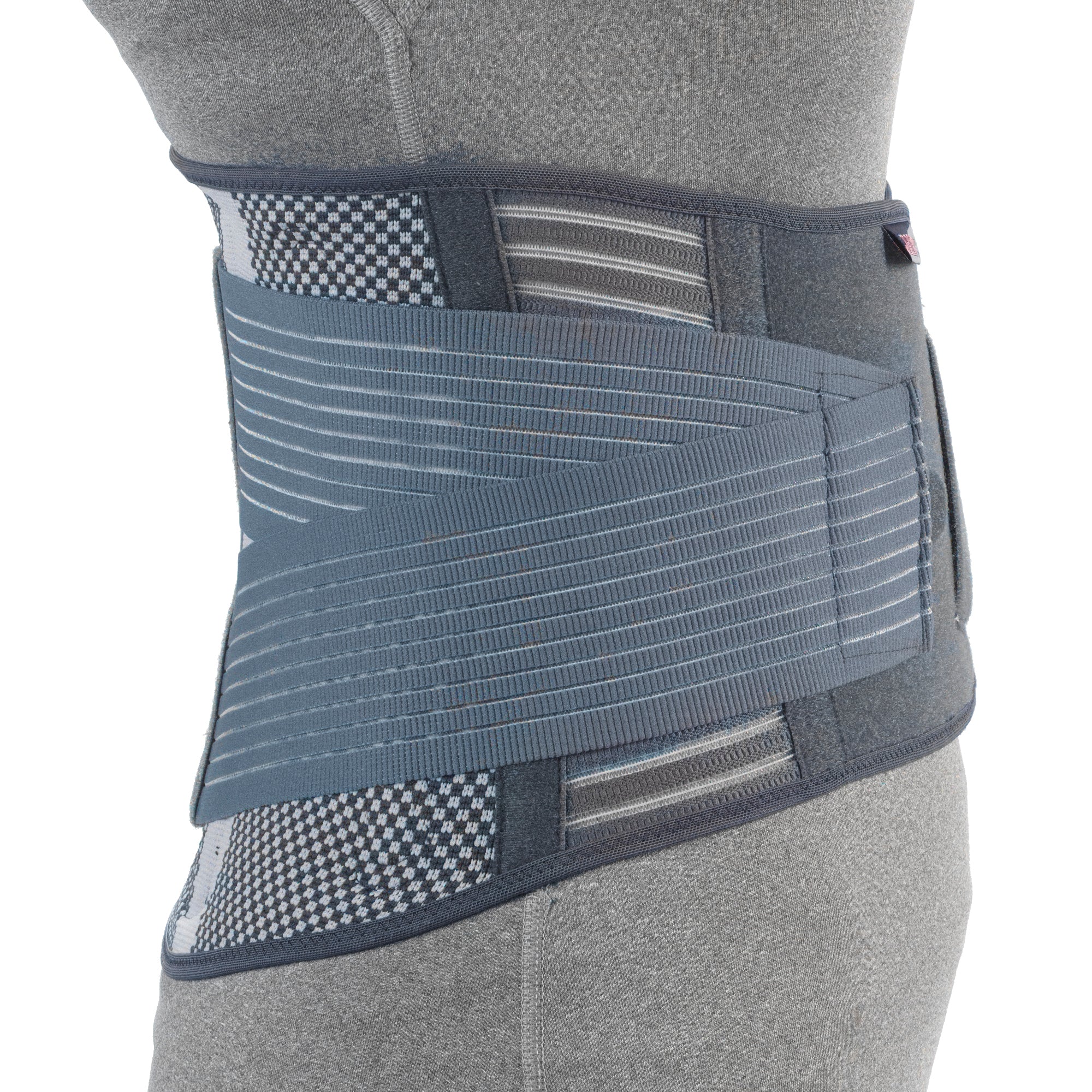Close-up side angle of OTC 2882 Theratex lumbosacral support on mannequin showing ribbed elastic panel, diagonal tension straps, mesh ventilation panels, and side velcro pull strap in grey