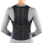 OTC Comfort Posture Brace with Rigid Stays in black – rear view worn by a person in a grey long-sleeve shirt, showing breathable mesh back panel, vertical rigid stays, criss-cross lumbar straps, and lower back support band on white background