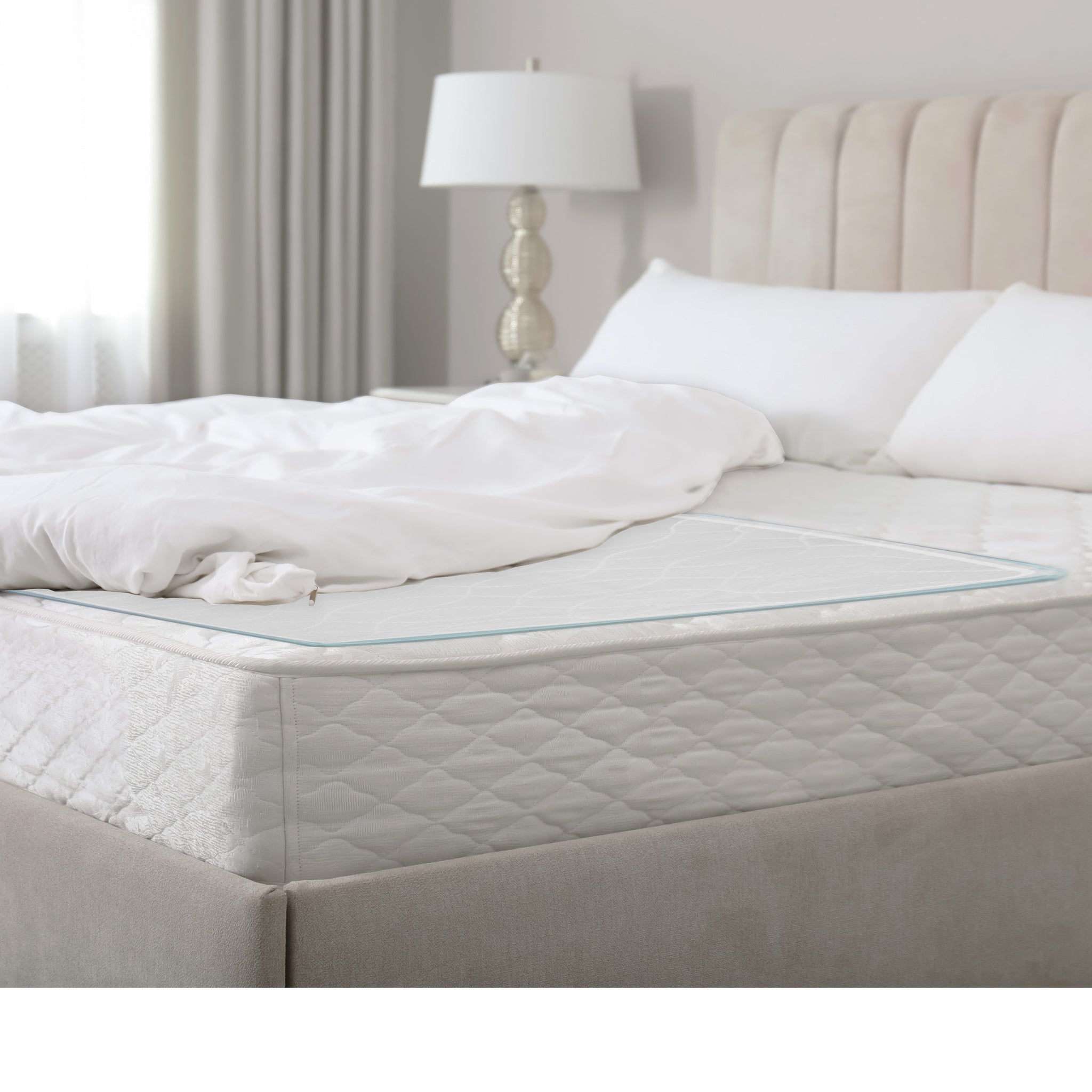Reusable waterproof bed pad laid flat on a mattress in a bright neutral bedroom – showing full coverage and teal edge binding – Must
